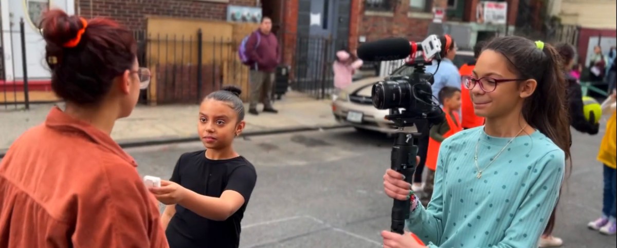 two students filming a teacher in an open streets event